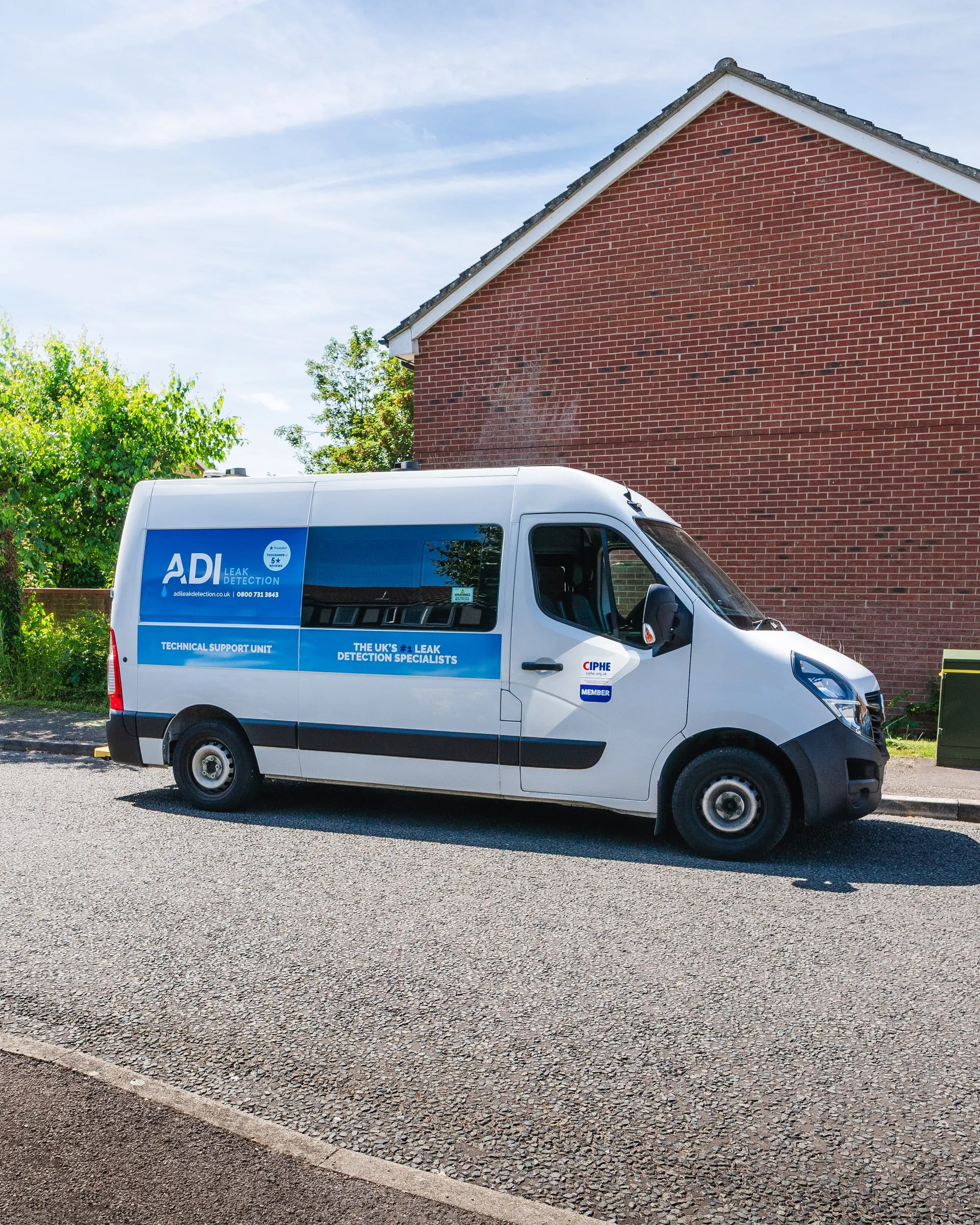ADI van parked on a residential street beside a red-brick house