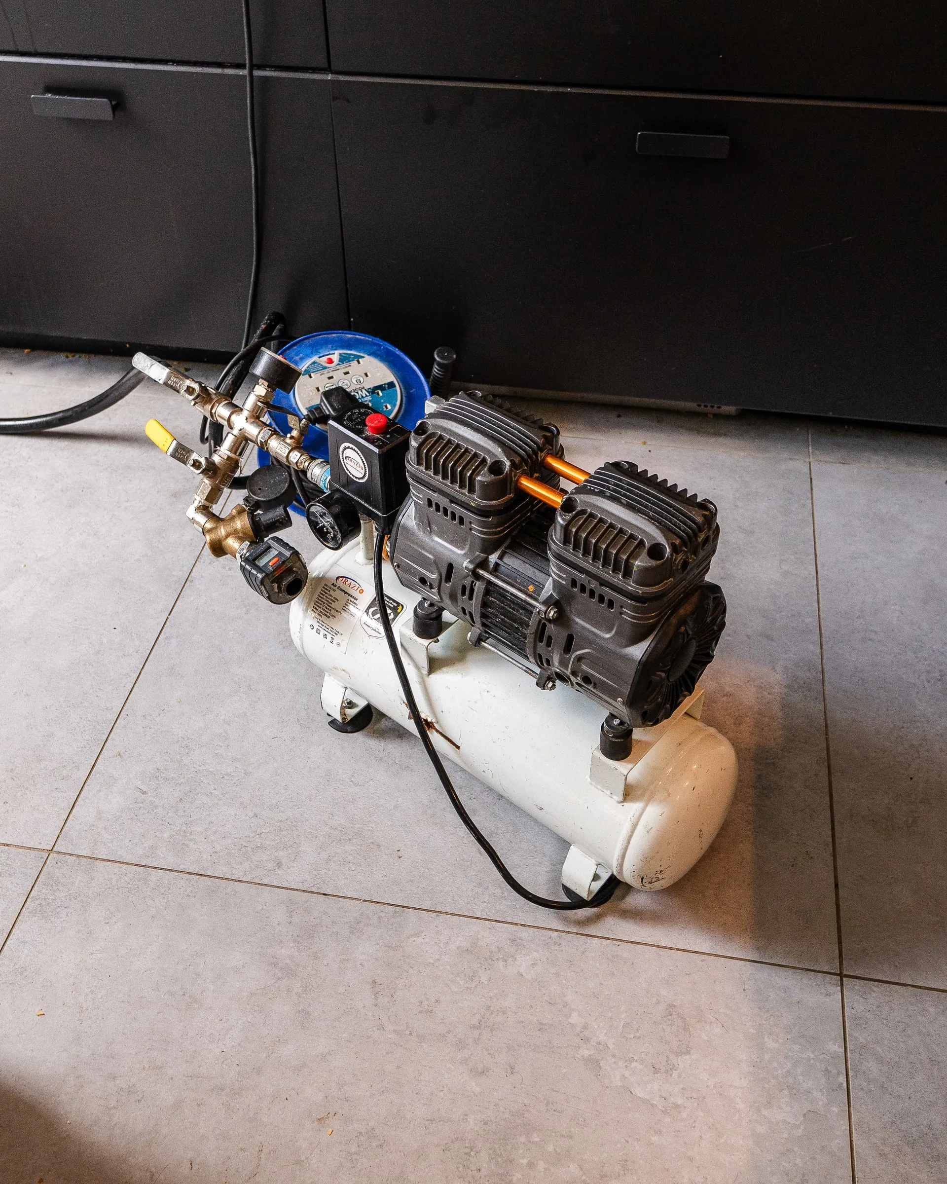 Compressor and pressure gauge set up on a tiled floor ready for a pressure test