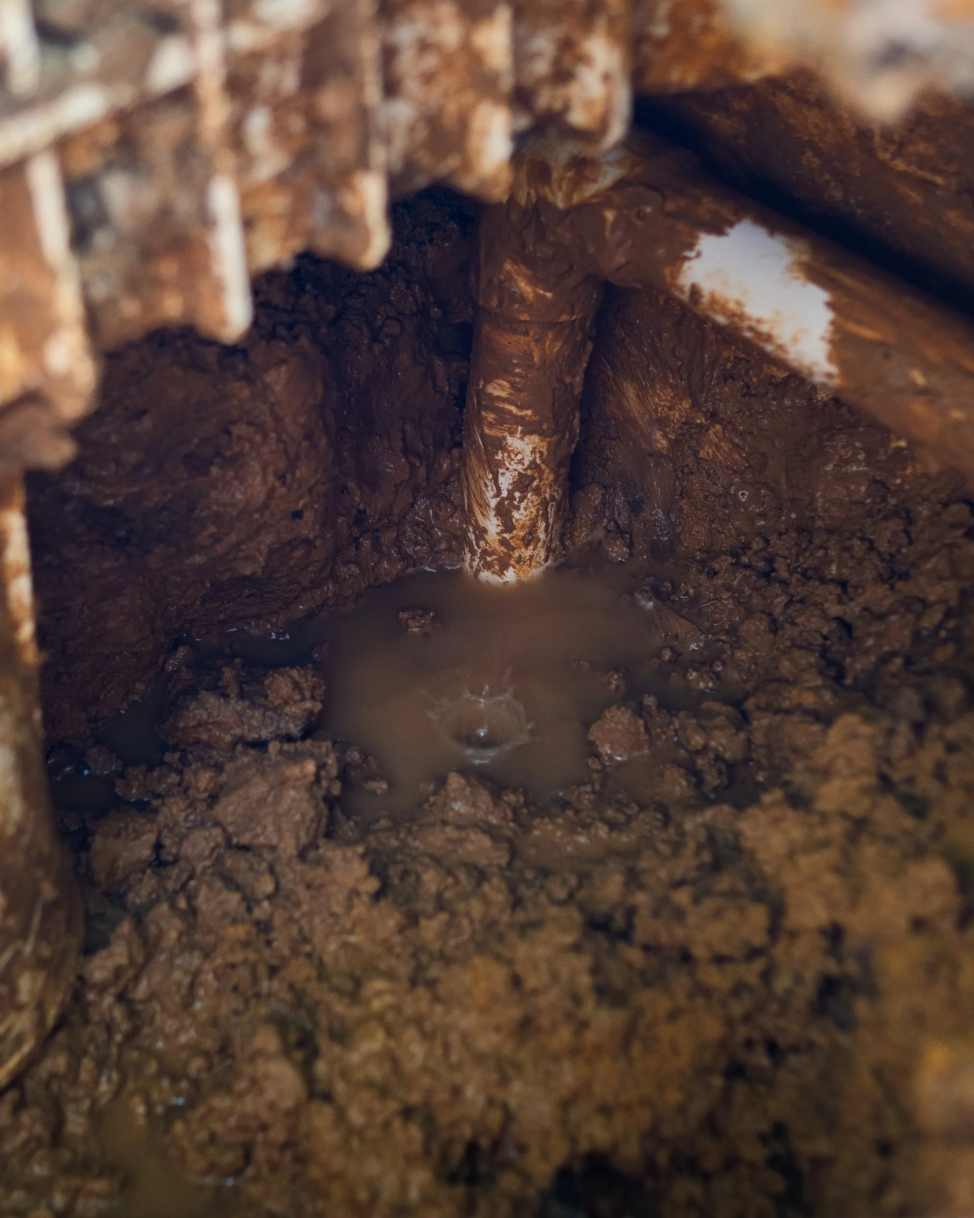 A pipe exposed in a wet excavation, with water bubbling up around it
